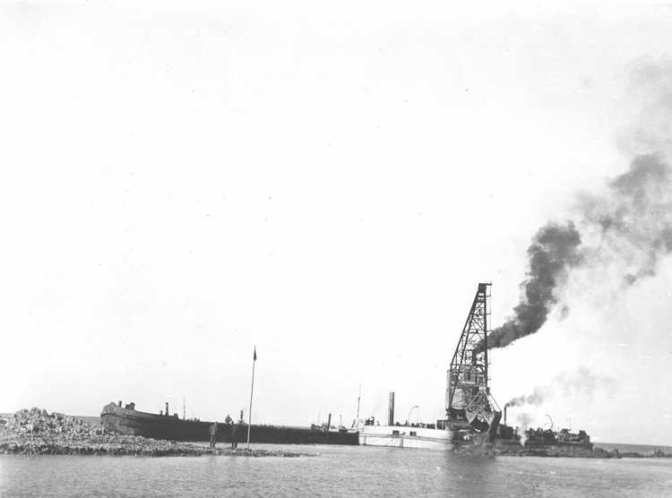 Een kraan van de MUZ lost een lading keileem in de Afsluitdijk, ca. 1932 