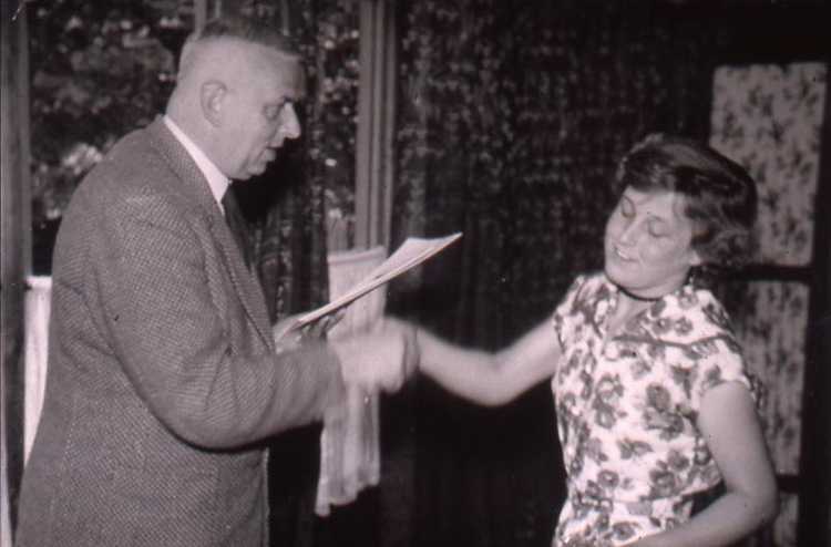 Burgemeester Keijzer reikt het getuigschrift van de huishoudschool uit aan Fem, circa 1953
