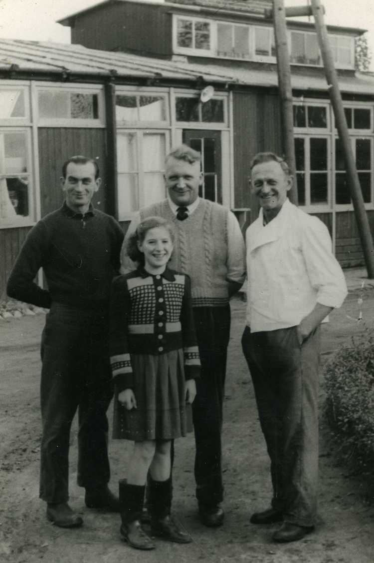 Martha in kamp Vollenhove met kok Vis (links), kok Jan van Urk (rechts) en haar vader (midden). Op de achtergrond de kampkeuken met verhoogd dak, ca. 1947 (privécollectie familie Appels)